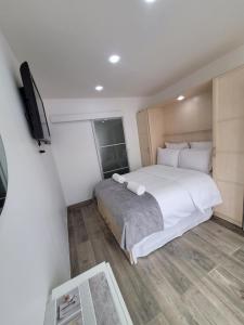 a bedroom with a white bed and a flat screen tv at Studio 1 à La Trinité proche de Nice, Monaco et l'Italie in La Trinité