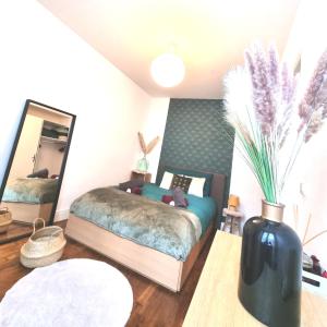 a bedroom with a bed and a vase with feathers at Joli Appartement 20 minutes Paris, Orly, CDG, Disney, Wi-Fi & Netflix in Le Perreux-Sur-Marne