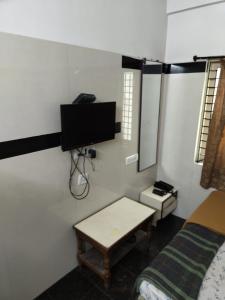 Habitación con cama, TV y mesa. en Devi Deluxe Lodge By WB Inn, en Secunderābād