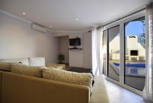 een woonkamer met een bank en uitzicht op een zwembad bij Villa Prestige Five Sea View Marina By TatiHomes in Albufeira