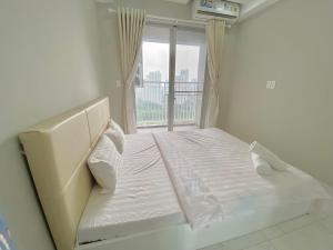 a white bed in a room with a window at Scenic Valley Marvel in Ho Chi Minh City