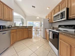 a kitchen with wooden cabinets and a stove top oven at Ainsdale Haven home in Kissimmee