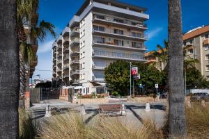 een hoog wit gebouw met een bank ervoor bij AT129 Apartamento en primera línea de la playa in Torredembarra