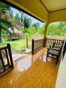 a porch with two chairs and a view of a yard at Puring Bungalows in Gili Air