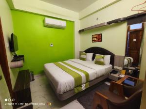 a green room with a bed and a tv at Hotel Prabhat in Varanasi