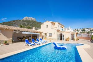 una piscina con sillas azules y una casa en Villa Ivars by Abahana Villas, en Calpe