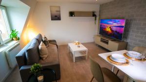 ein Wohnzimmer mit einem Sofa und einem Flachbild-TV in der Unterkunft # Le 4 # Très beau appartement T3 Neuf, tout confort, Mulhouse centre ville in Mulhouse