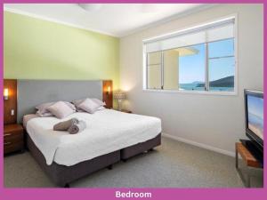 een slaapkamer met een bed, een raam en een televisie bij 52 Airlie Beach Beauty at The Summit in Airlie Beach