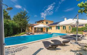 a pool with chairs and umbrellas in front of a house at Nice Home In Rezanci With Wifi in Režanci