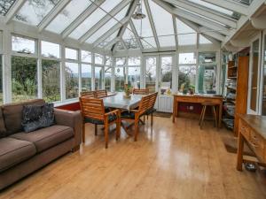 a conservatory with a table and chairs and a couch at Hill Brow in Acton Scott