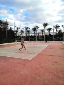 Um homem está a andar num campo de ténis. em Queen Sharm Italian Club em Sharm El Sheikk
