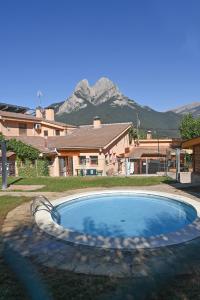 a swimming pool in front of a house with mountains at Bungalows del Camping Pedraforca in Saldés