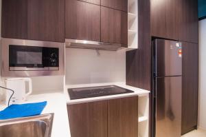 a small kitchen with a refrigerator and a stove at Lumi Tropicana Petaling Jaya by Idealhub in Petaling Jaya