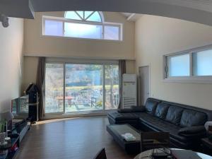 a living room with a couch and a large window at Gapyeong Casa Swiss Pension in Gapyeong