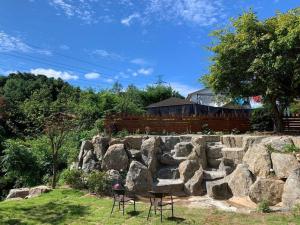 a stone wall with two chairs in a yard at Gapyeong Casa Swiss Pension in Gapyeong