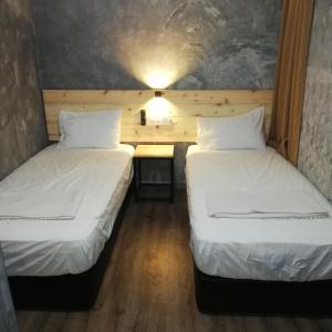 Duas camas num pequeno quarto com uma secretária. em Myera Hotel em Banting
