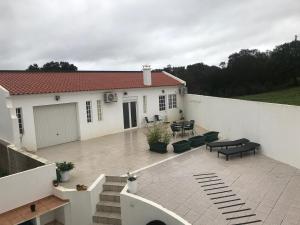 a white house with a patio with tables and benches at Le Nid D’Abela in Abela