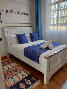 a bedroom with a white bed with blue pillows at Wellstaycation in Bungoma