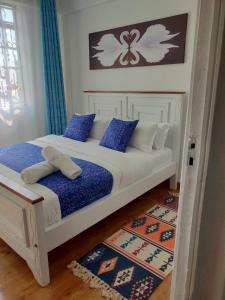 Un dormitorio con una cama blanca con almohadas azules y blancas en Wellstaycation, en Bungoma