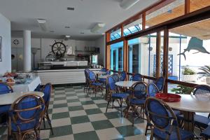 a restaurant with tables and chairs and a kitchen at Hotel Bagni Arcobaleno in Deiva Marina