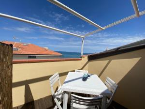 een witte tafel en stoelen op een balkon met uitzicht op de oceaan bij Luci in San Vincenzo