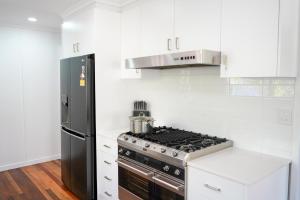 a white kitchen with a stove and a refrigerator at The Beach House in Pallarenda