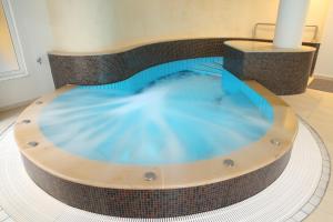 a jacuzzi tub in a building with blue water at Palace Hotel Hévíz in Hévíz +64 photos