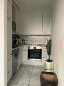 una cucina con mobili bianchi e un forno a piano cottura di Ferienwohnung Sonnenschein a Grenzach-Wyhlen