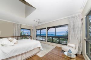 a bedroom with a white bed and large windows at Denham Heights in Townsville