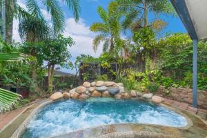 a swimming pool with a rock wall and trees at Denham Heights in Townsville