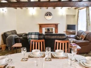 a living room with a table and leather furniture at Stable Cottage in Askrigg