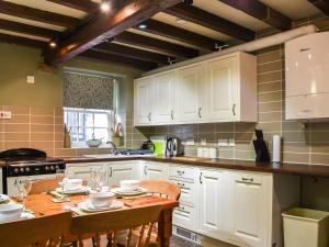 a kitchen with white cabinets and a wooden table at Stable Cottage in Askrigg