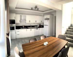 - une cuisine avec une table en bois et des placards blancs dans l'établissement Nokta Park I 4+1 Villa, Özel Havuzlu, à Fethiye