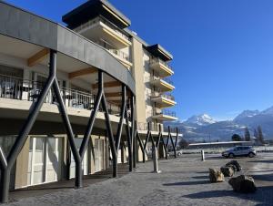 un parcheggio di fronte a un edificio con montagne di Alp Art Hotel a Collombey