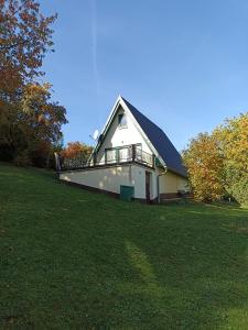 a white house with a balcony on a grass field at Bungalow Sud-Harz Bleicherode onder in Bleicherode