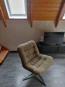 a brown chair in a living room with a tv at Bungalow Sud-Harz Bleicherode onder in Bleicherode