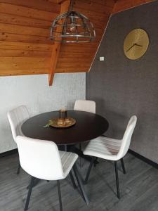 a dining room with a black table and white chairs at Bungalow Sud-Harz Bleicherode onder in Bleicherode +11 photos