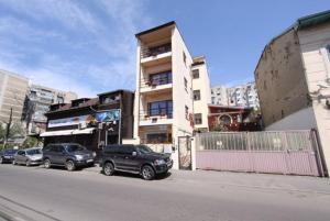 two cars parked in front of a building on a street at Ave Hotel Victoriei in Bucharest