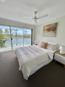 a white bedroom with a bed and a large window at Tranquil Oasis on Pine Lake in Gold Coast