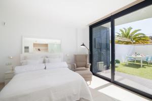 a white bedroom with a large bed and a balcony at Luxury Avilla Las Olas in Palm-Mar