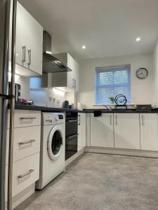 cocina con armarios blancos, lavadora y secadora en 1 Merchants Gate - 2 bedroom, city apartment with private parking en York