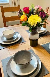 einem Holztisch mit zwei Platten und einer Vase aus Blumen in der Unterkunft 1 Merchants Gate - 2 bedroom, city apartment with private parking in York