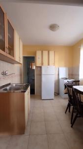 a kitchen with a white refrigerator and a table and chairs at Apartment in nature in Bijela