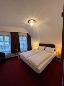 a bedroom with a large white bed with two windows at Hotel Columbus und Glamping in Bremerhaven