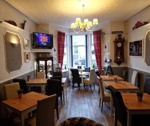 a restaurant with wooden tables and chairs and a tv at Newholme Hotel in Blackpool