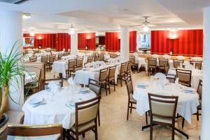 a restaurant with white tables and chairs and red curtains at Hôtel Saint Sauveur in Lourdes