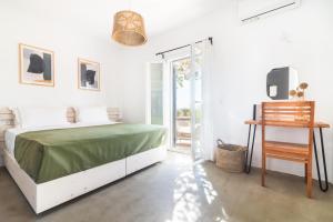 a white bedroom with a green bed and a sliding glass door at Statheros Garden in Antiparos