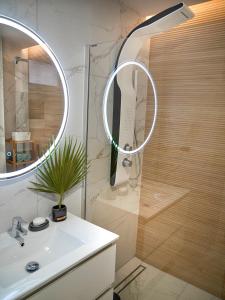 een badkamer met een wastafel en een douche met een spiegel bij TENERO APARTAMENTO TENERIFE EL DORADO in Playa de las Americas