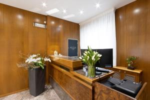un ufficio con pannelli in legno e una scrivania con fiori di Hotel Pittini a Gemona del Friuli