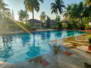 uma piscina com palmeiras num resort em Villa Cavelossim em Cavelossim